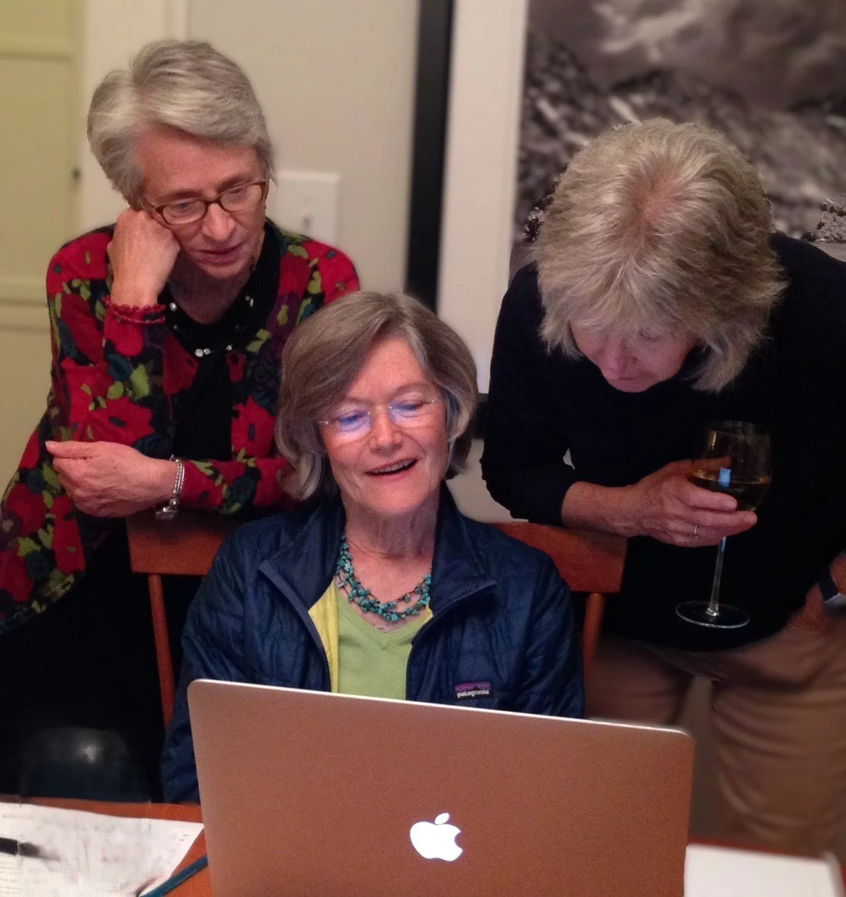 three women gathered over computer screen