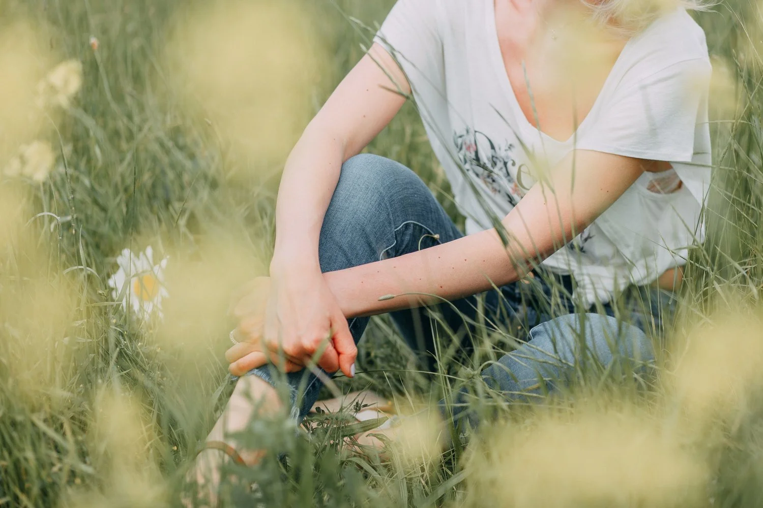 Woman sitting mindfully in a wildflower meadow, representing embodied practice for somatic practitioners and coaches