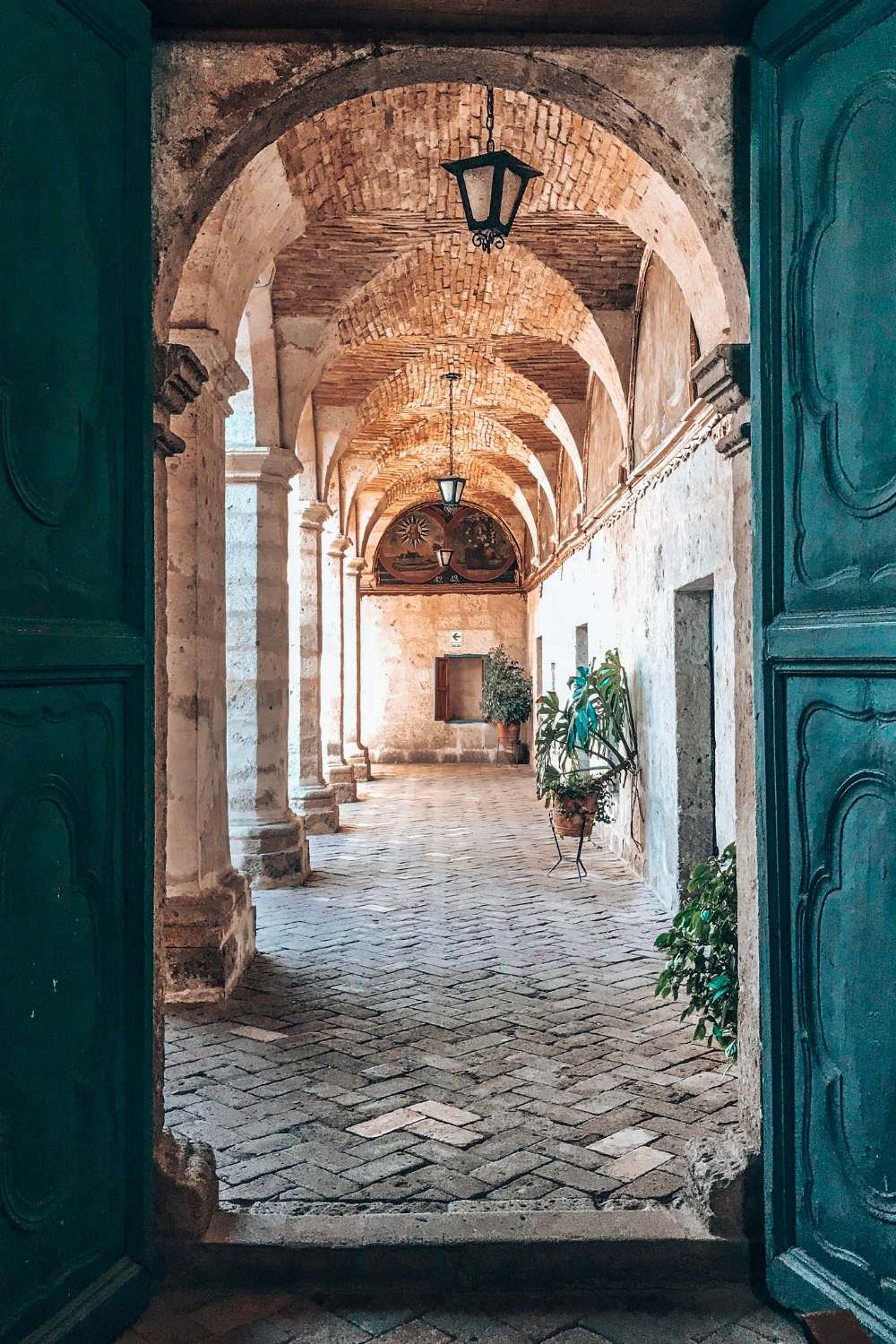 Open turquoise doors revealing a sunlit stone archway, symbolizing the doorway of personal transformation