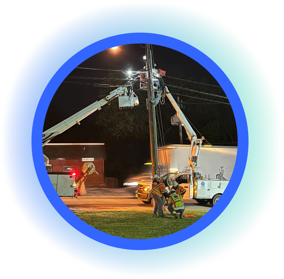Two Planet Networks bucket trucks and workers at night working on telephone pole