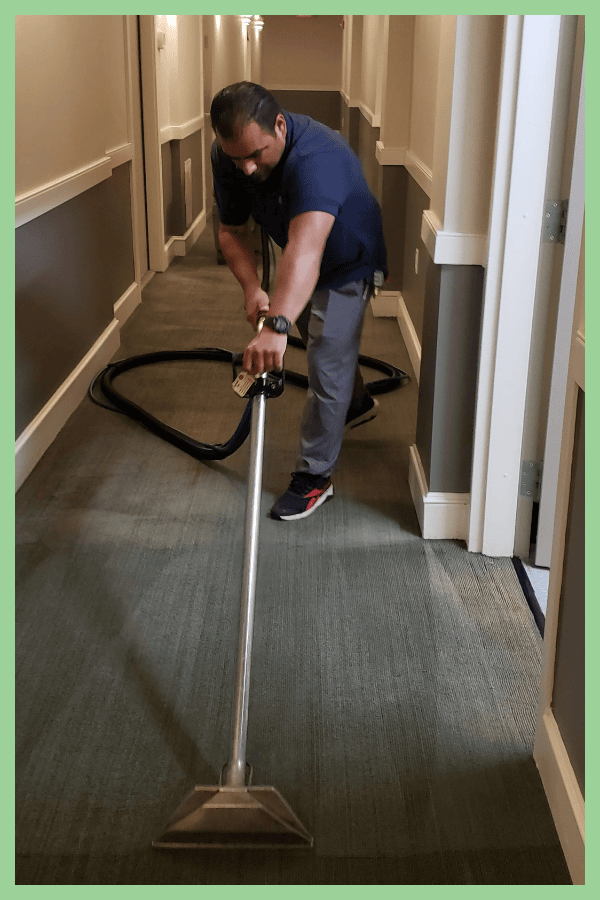 A CPC worker cleaning a commercial building hallway.