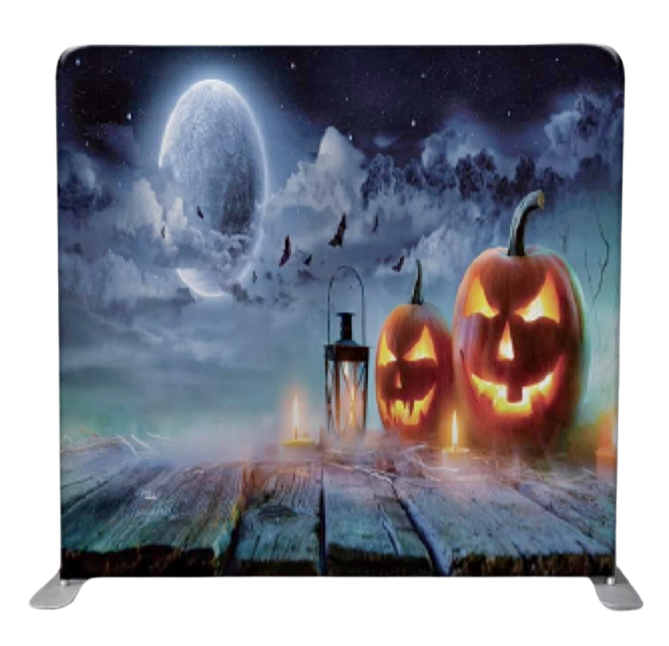 Halloween-themed scene with a full moon, bats, a cloudy sky, and three carved pumpkin jack-o'-lanterns on a wooden surface with candles and lanterns.