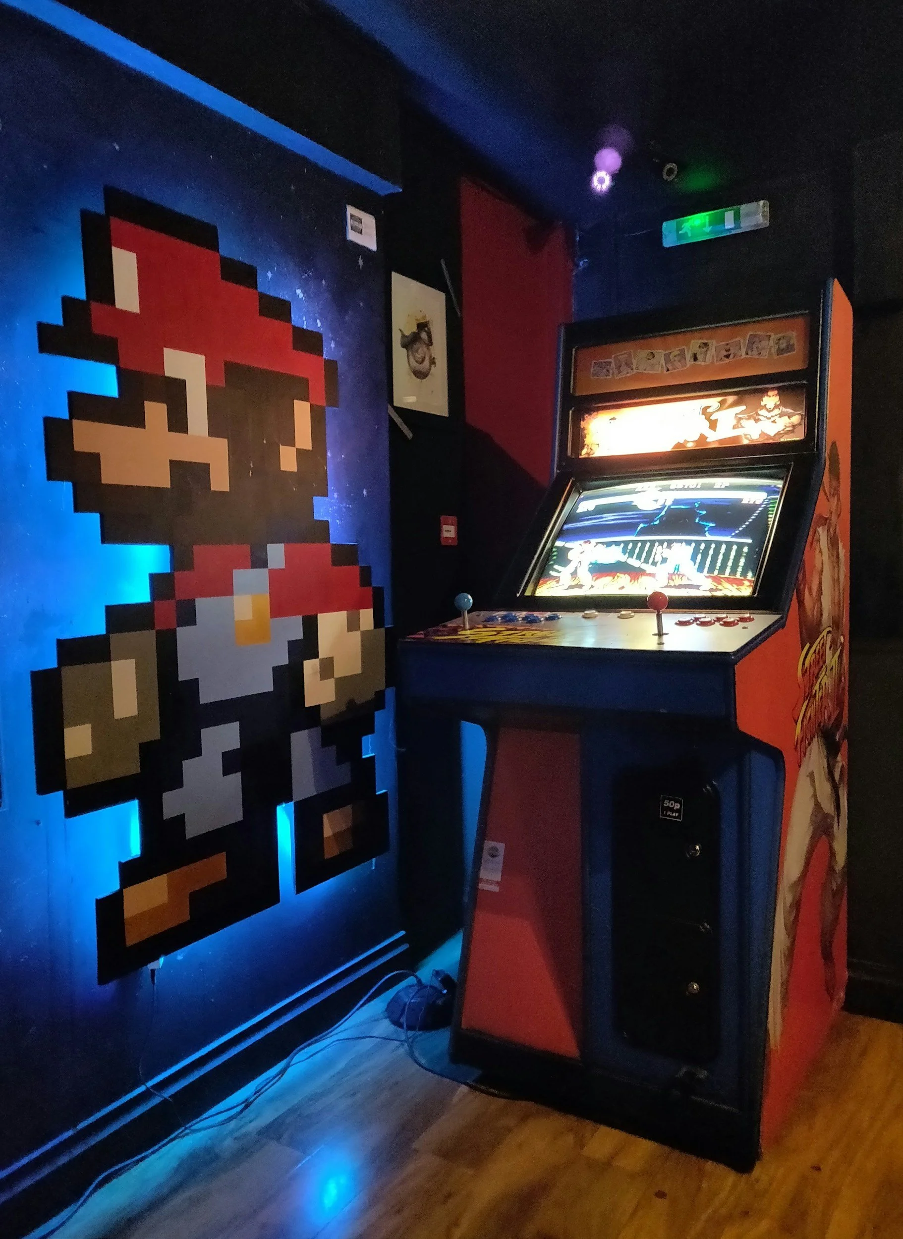 an arcade game and a microbit mario sticker on the wall