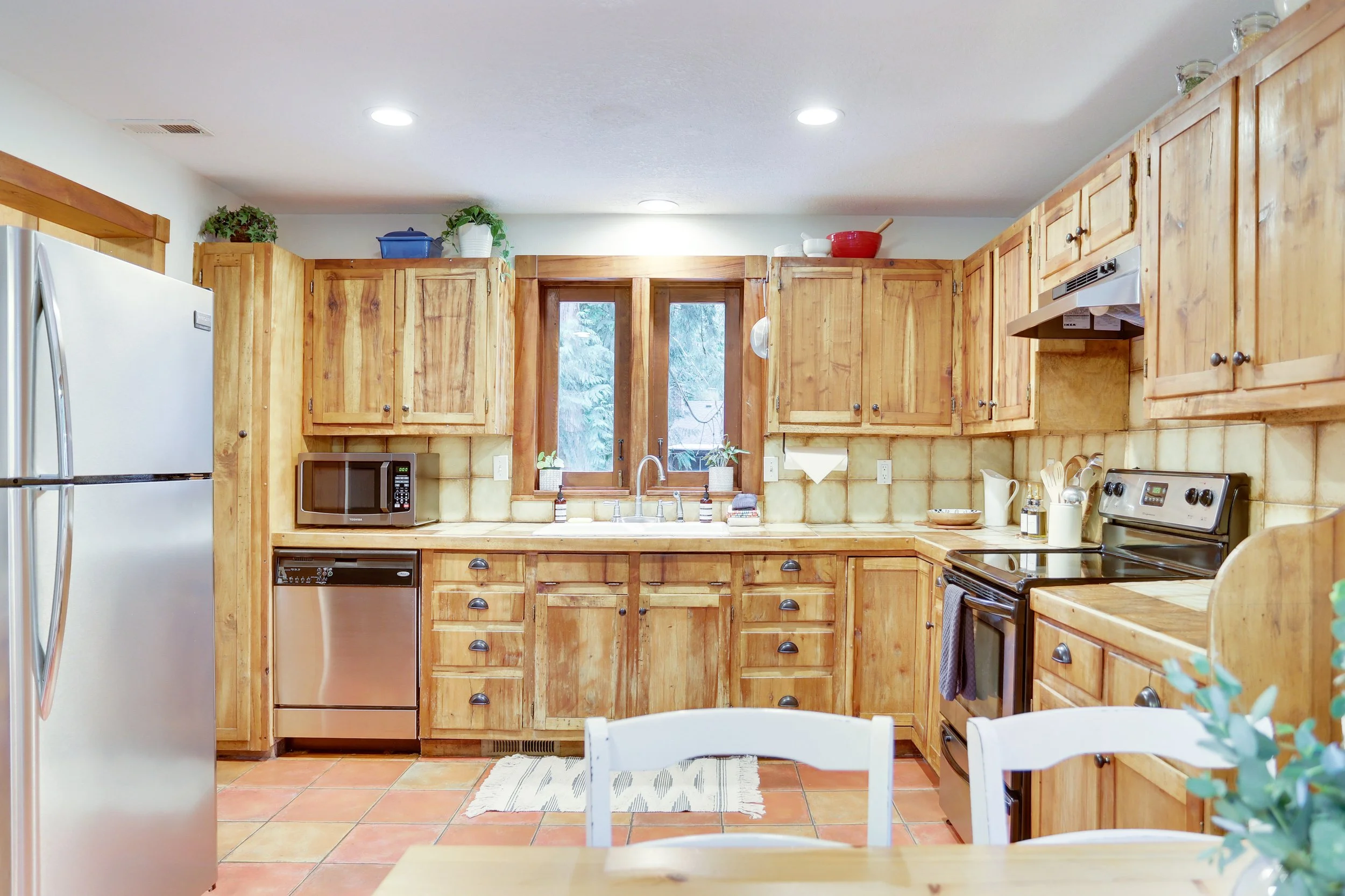 The cabin feel of wood cabinets and terracotta tiles paired with modern, stainless appliances provide a perfect blend of old and new world touches.