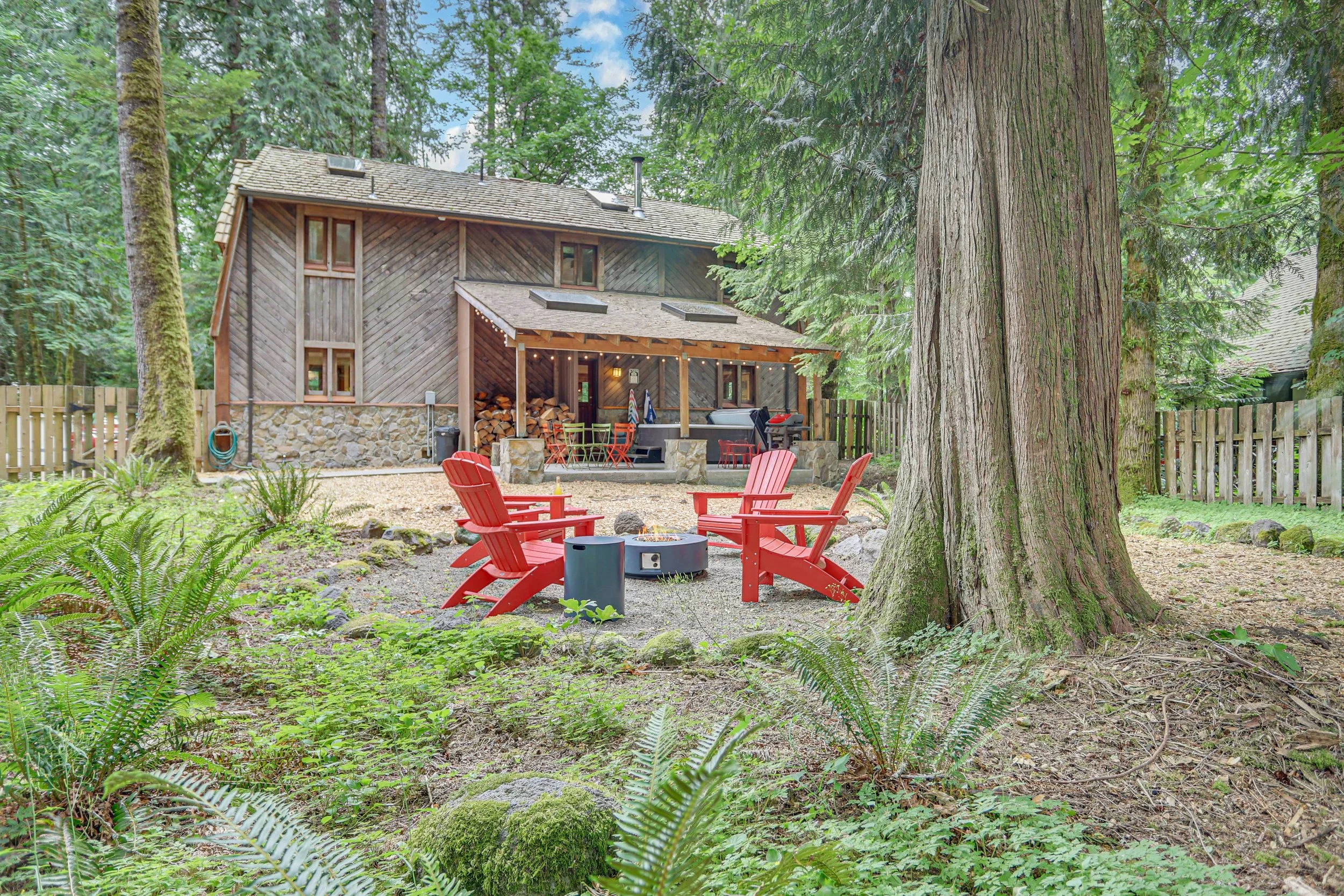 Adirondack chairs surround a gas fire pit in this large, fully fenced backyard.