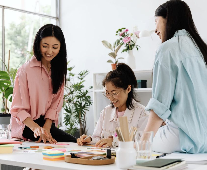 Three women working together at a table with notes and markers during hello DBT therapy.