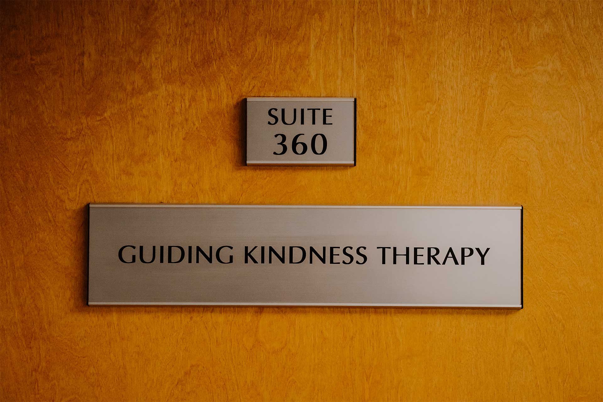 Guiding Kindness Therapy's wooden office door in Bala Cynwyd with signs reading “Suite 360” and “Guiding Kindness Therapy.”