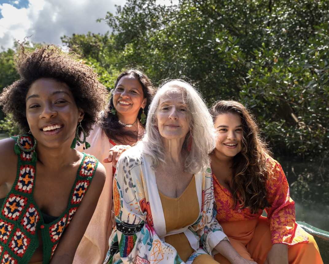 Group of women of different ages smiling together outdoors, representing connection and support in IFS therapy.