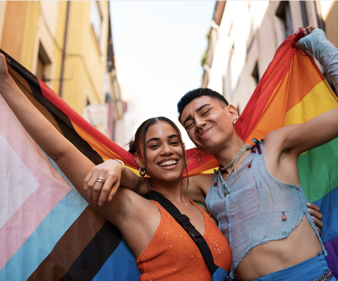 LGBTQ+ therapy focused on identity affirmation, emotional safety, and connection, shown through two people celebrating pride and self-expression together.