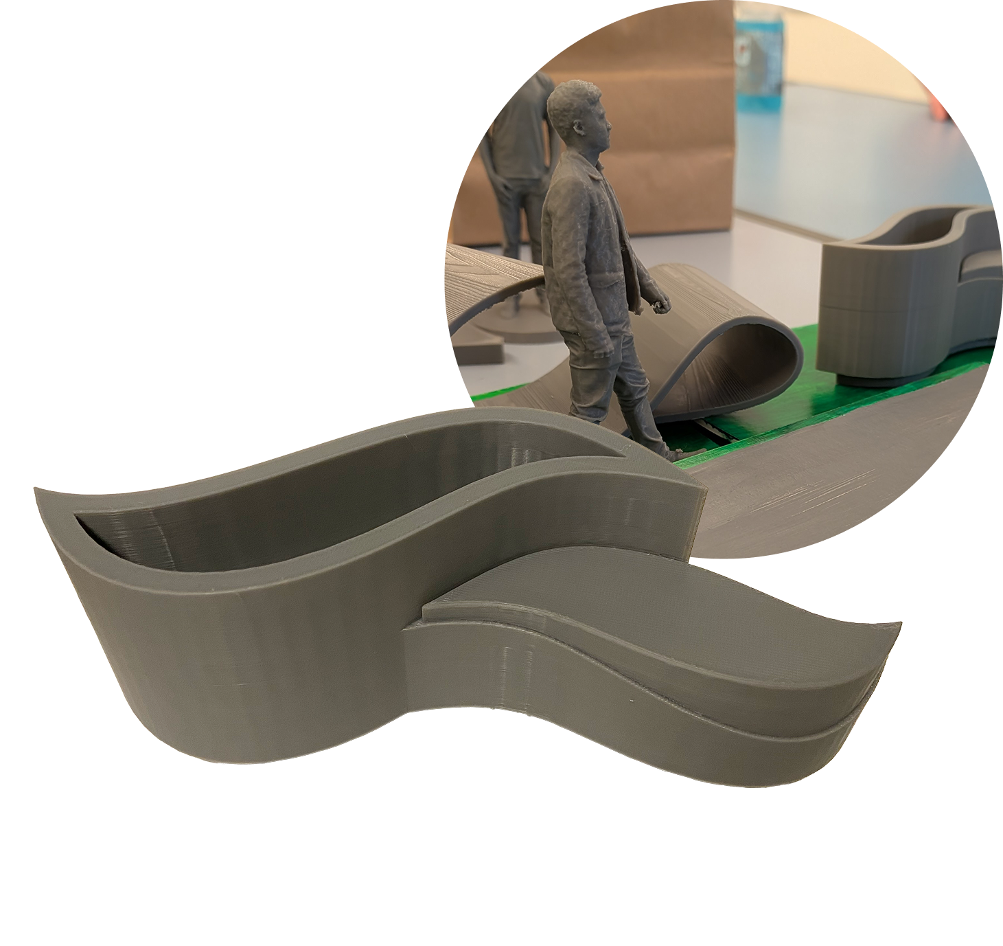 A small scaled model sculpture of a man walking on a curved pathway, surrounded by abstract, flowing shapes, possibly made from plastic or metal, with a background of office or workshop environment.