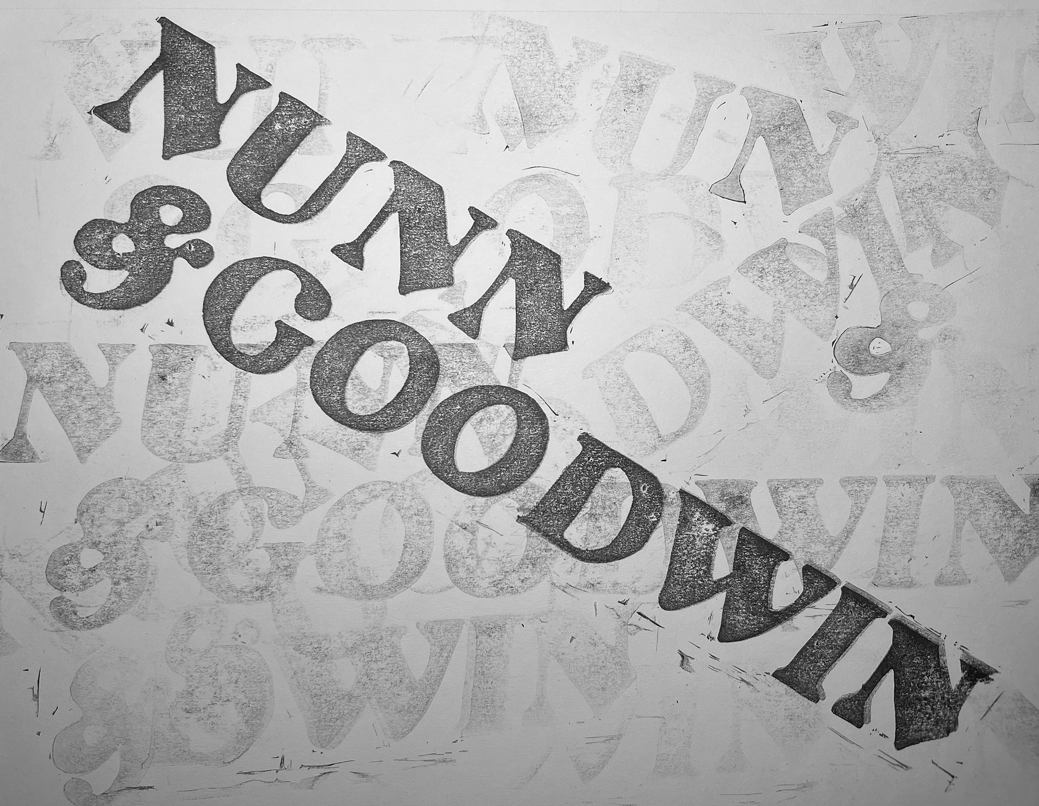 Black and white printed paper with overlapping letters and numbers, some of which are partially torn or obscured.