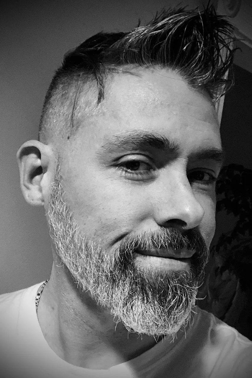Jeff Flowers close up shot in black and white. He is smirking and has a neatly trimmed salt and pepper beard.