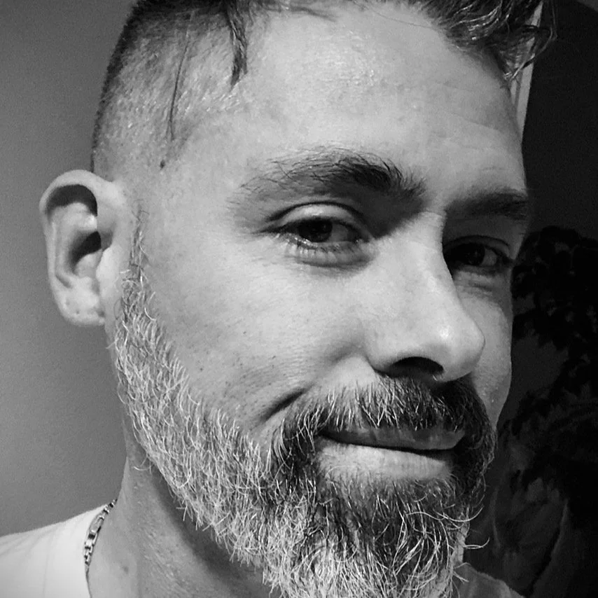 Jeff Flowers close up shot in black and white. He is smirking and has a neatly trimmed salt and pepper beard.