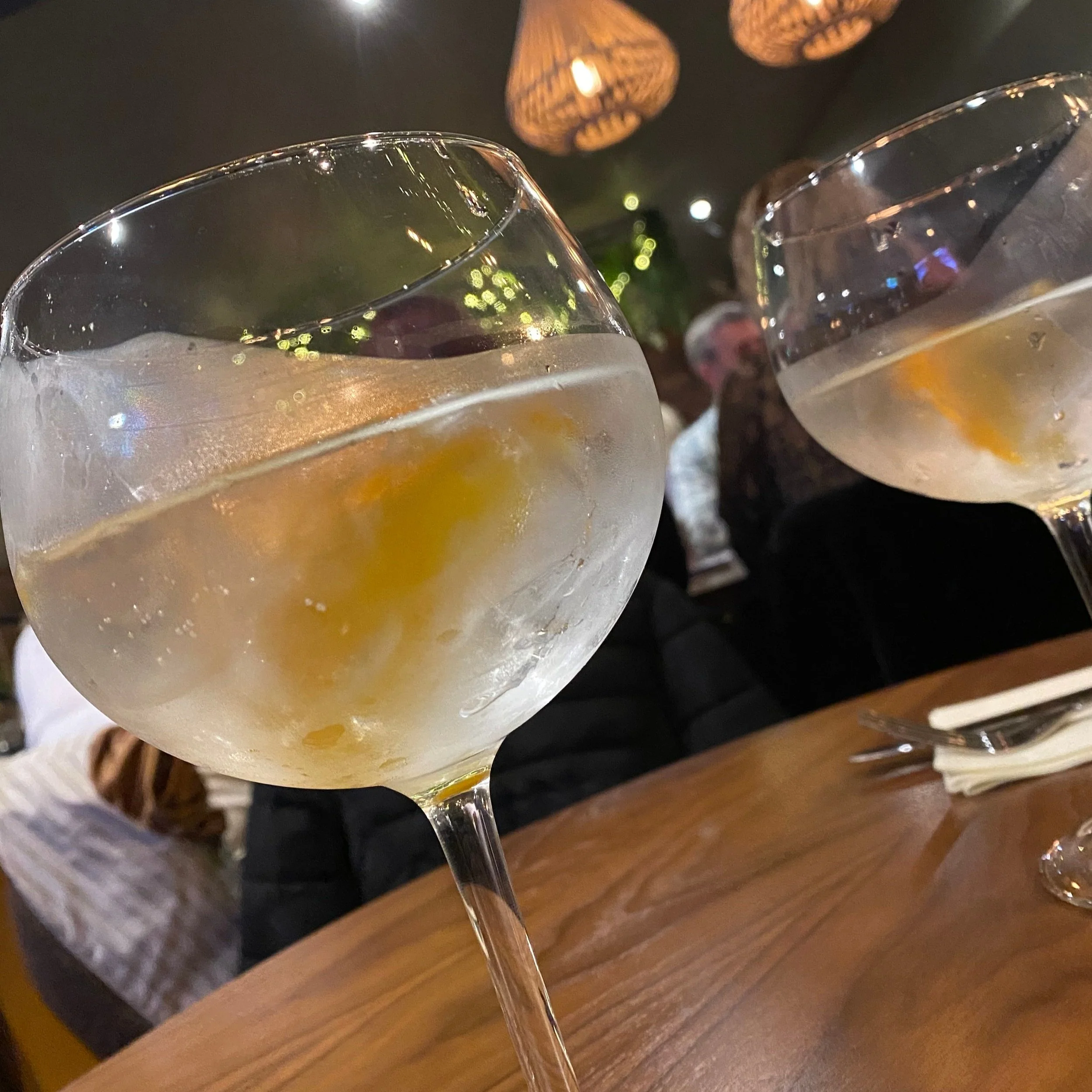 Anani Lawson is a certified sommelier. This image shows two chilled glasses of white wine on a dark wood table.