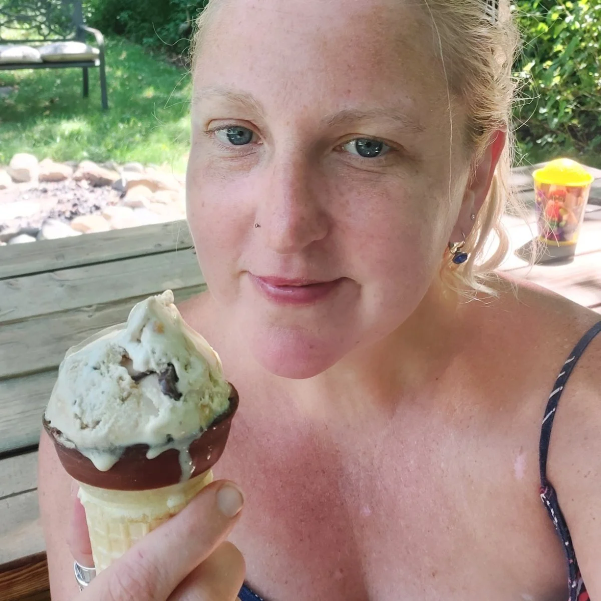 Courtney Crocker Stees pictured outside in a park. Her blond hair is pulled back and she's eating a slightly melted ice cream cone.