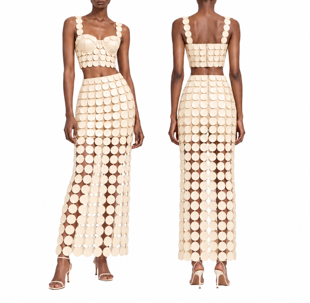 A woman modeling a beige dress made of large circular discs, shown from front and back. The dress features a crop top with wide straps and a high-waisted skirt with a sheer section at the bottom.
