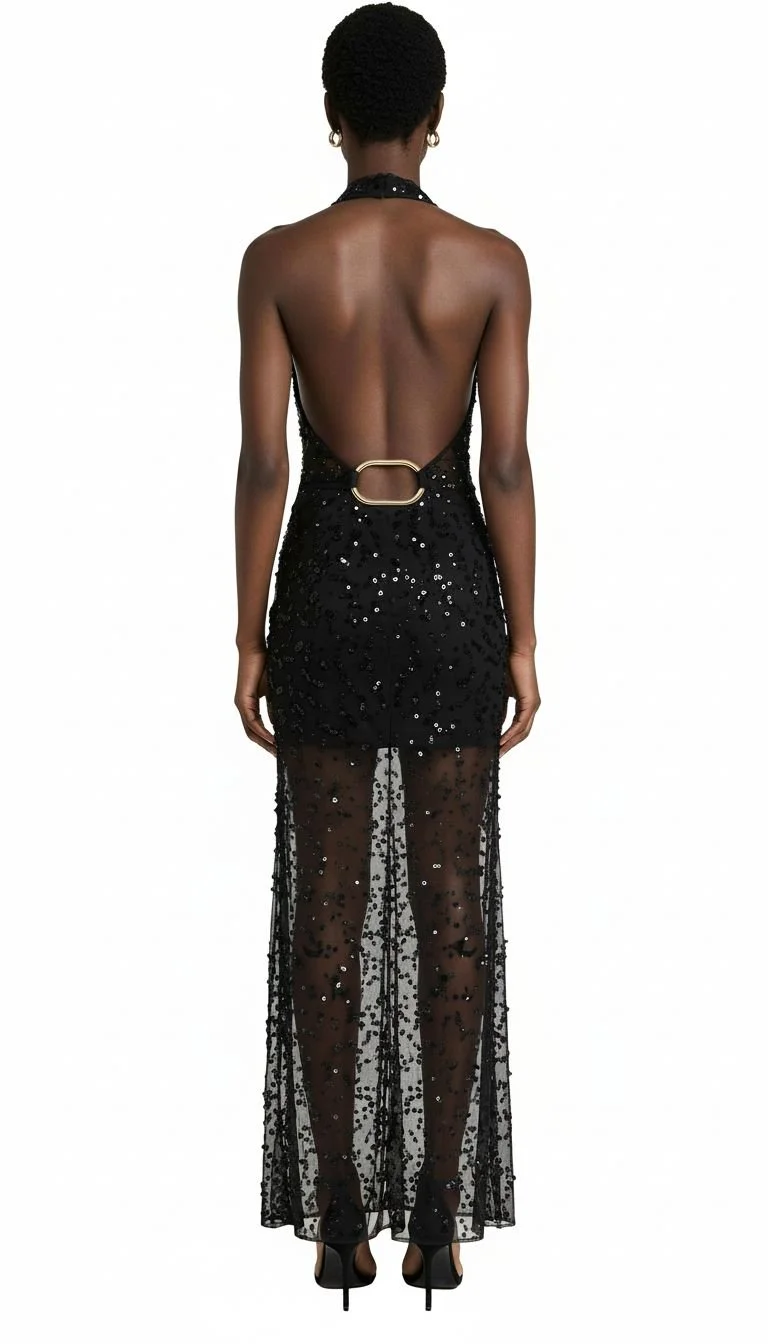Rear view of a woman wearing a backless black sequin dress with a sheer embroidered overlay and high heels.