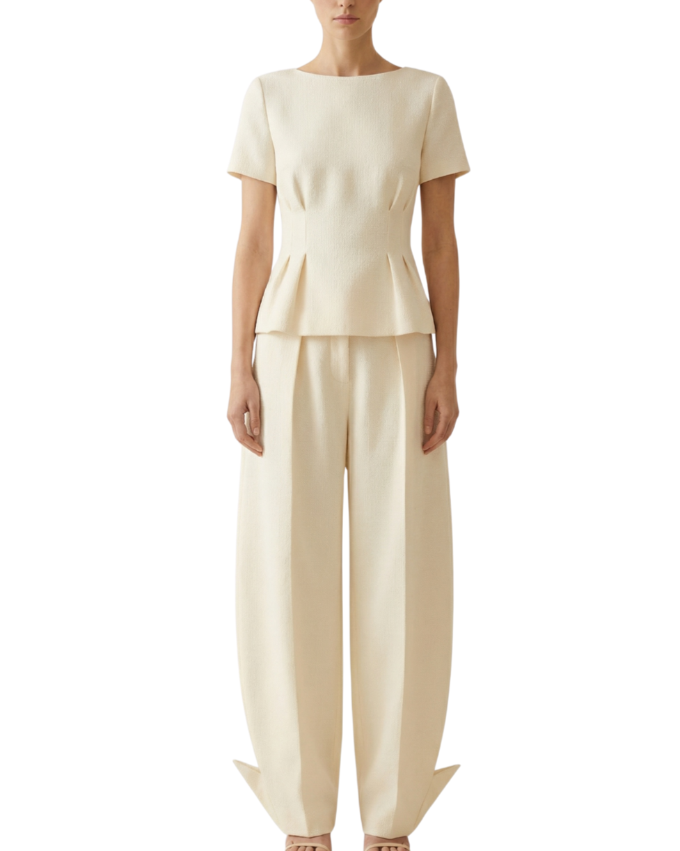 A woman wearing a cream-colored short-sleeve top and matching wide-legged pants.