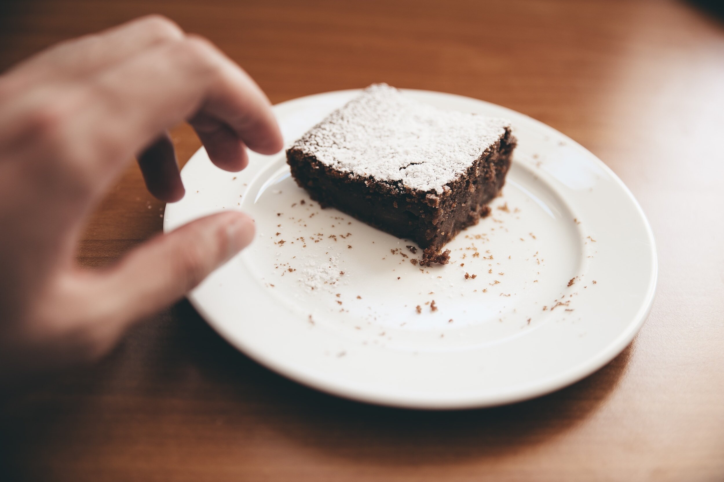 A hand reaching for a cake