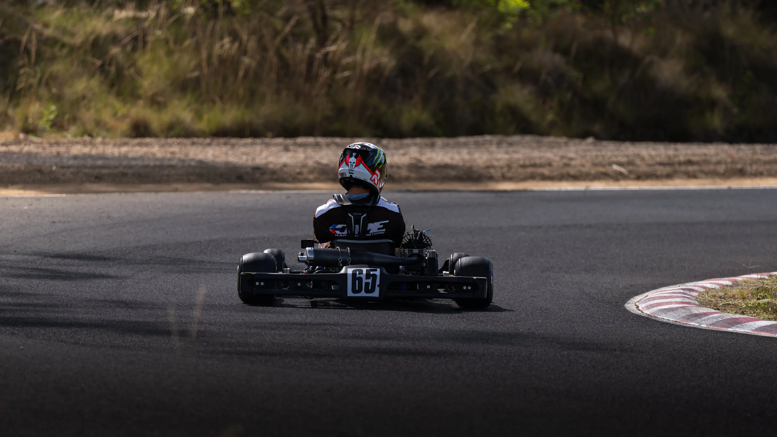 A person in a racing helmet driving a go-kart on a racetrack, taking a right turn.