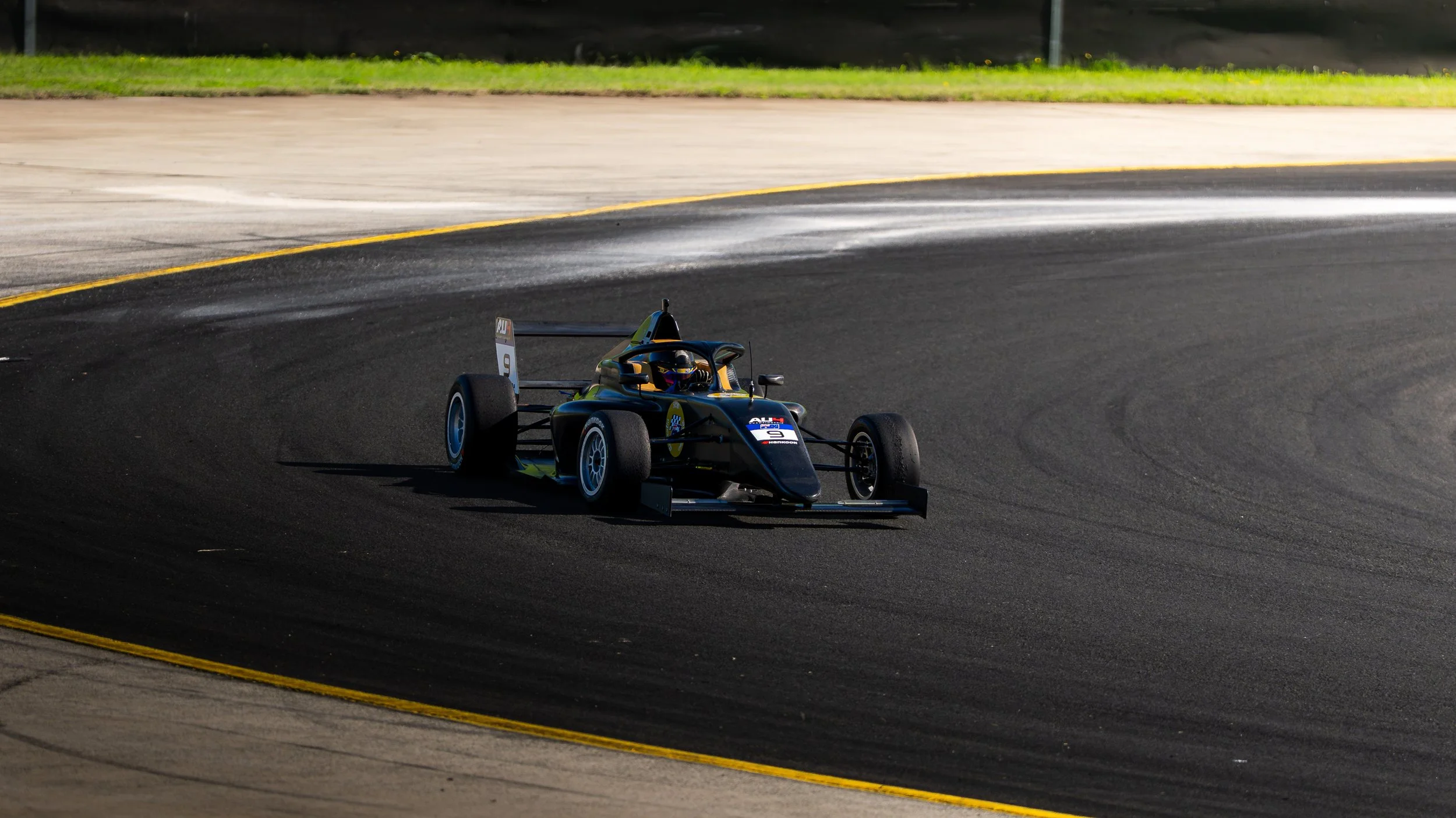 A race car speeding around a bend on a racetrack during daytime.
