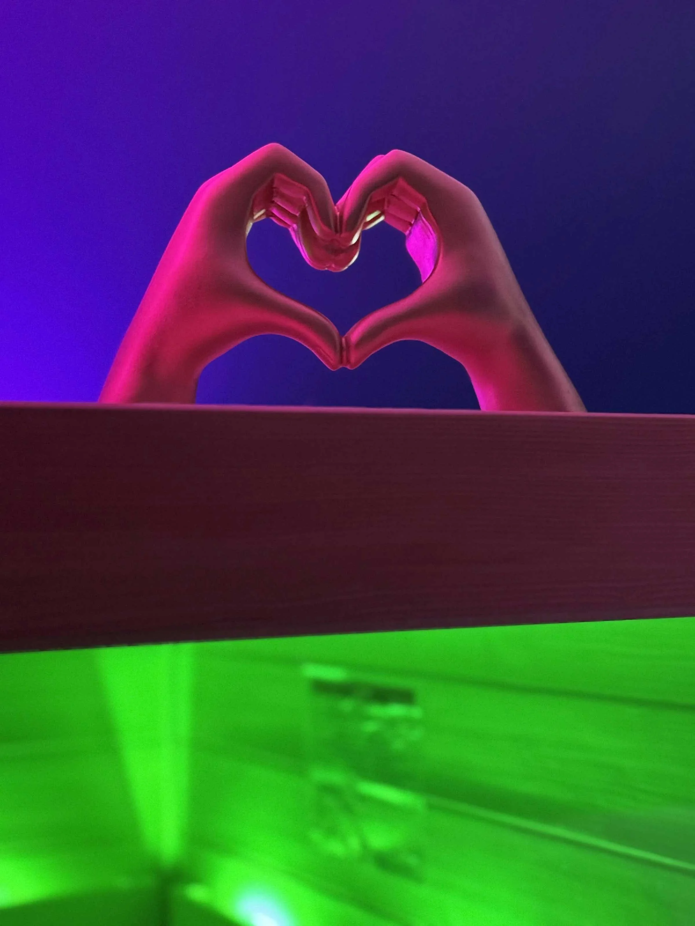 Two hands form a heart shape against a colorful background with pink, purple, and green lighting.