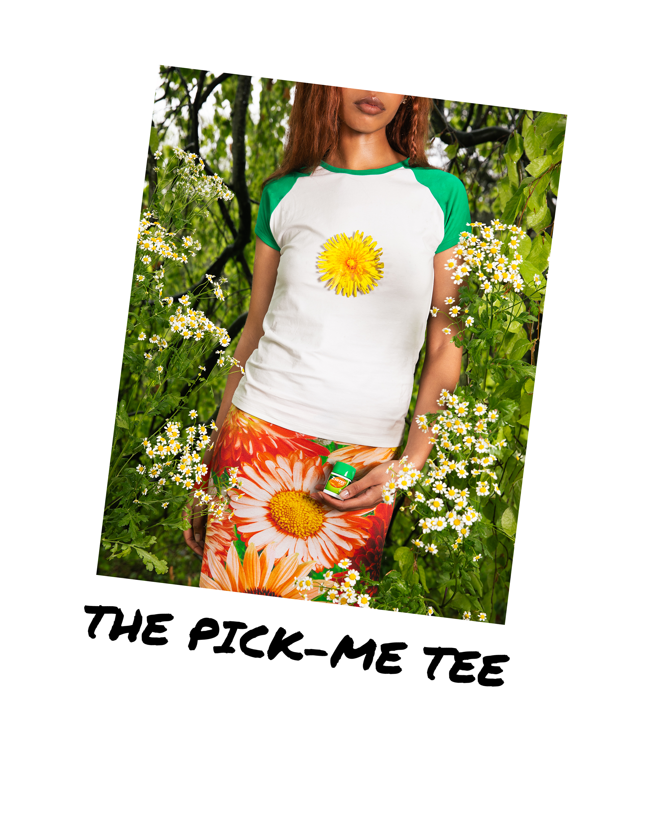 A woman standing among green plants and flowers, wearing a white and green t-shirt with a large yellow flower on the front, orange patterned pants, holding a bottle of ZYRTEC.