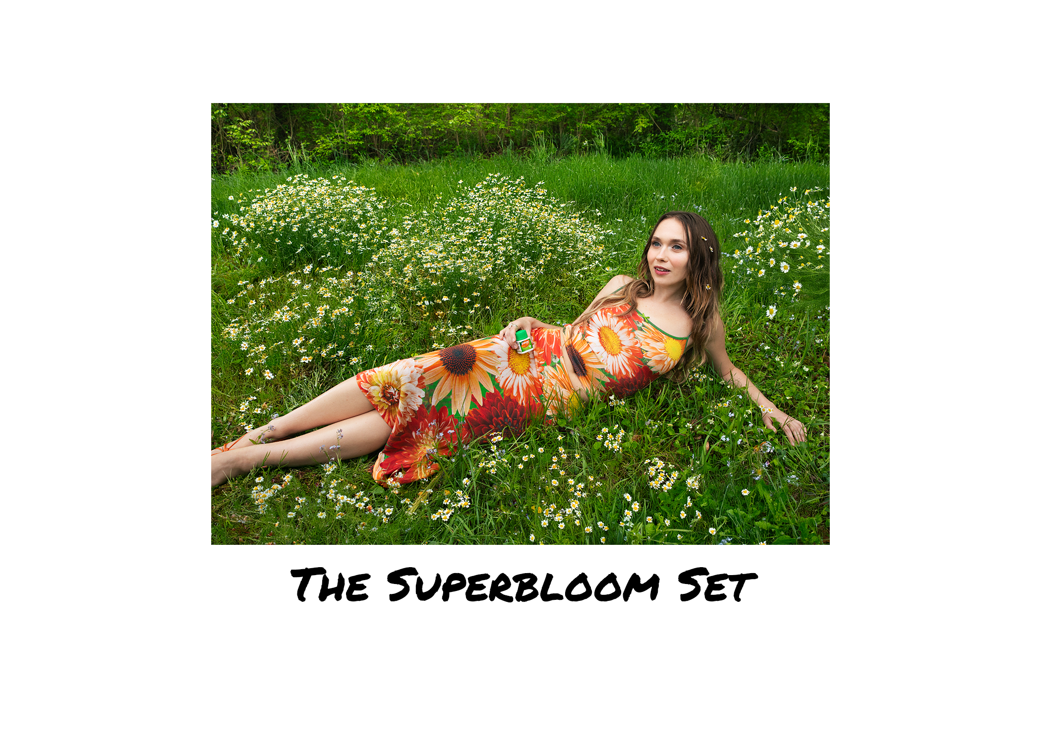 A woman in a floral dress lying on grass amidst wildflowers with a forest background, holding a bottle of ZYRTEC