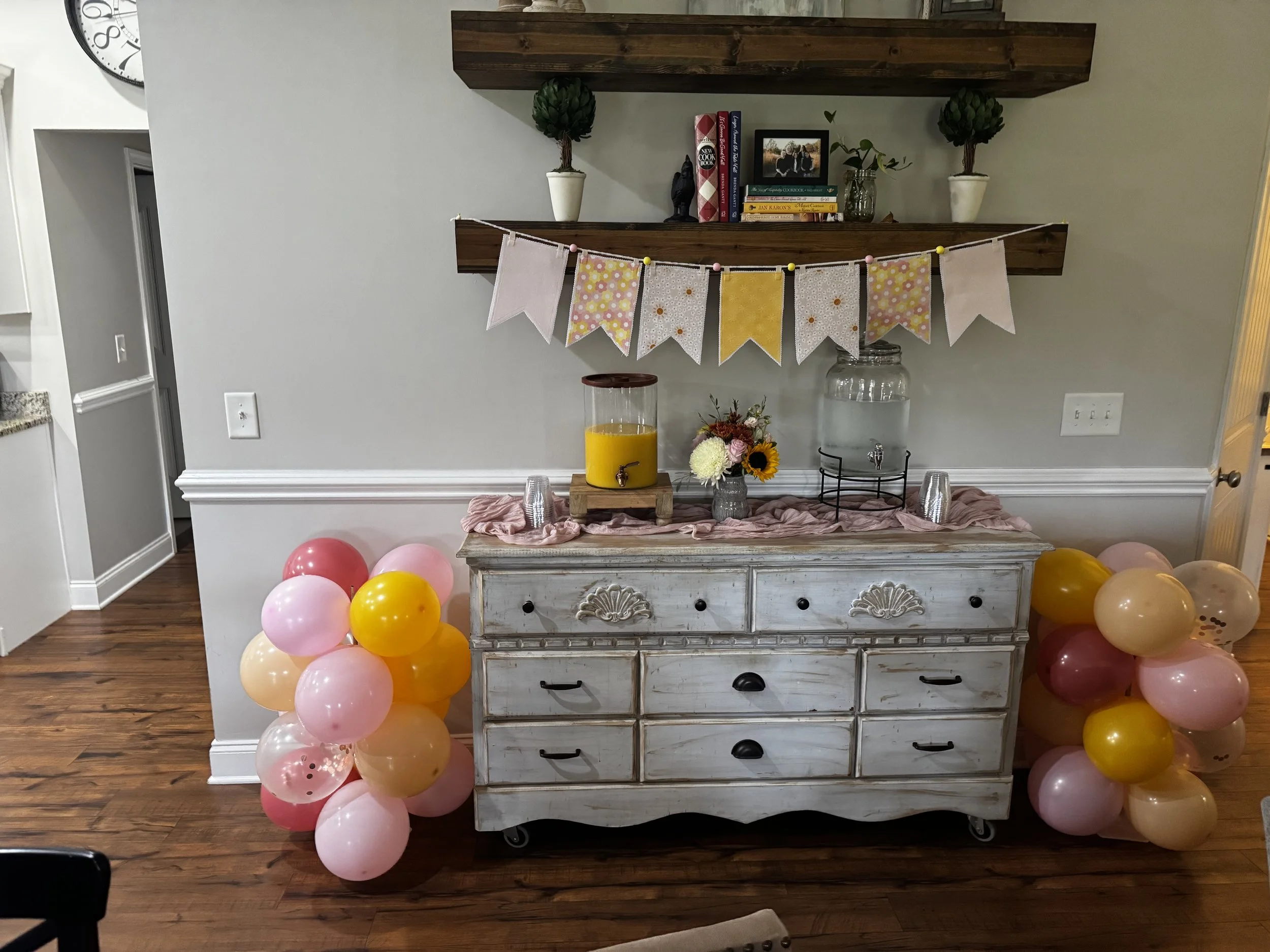 Coordinating handmade fabric pennant garland decorating a party table with pink and yellow balloons and seasonal floral accents.