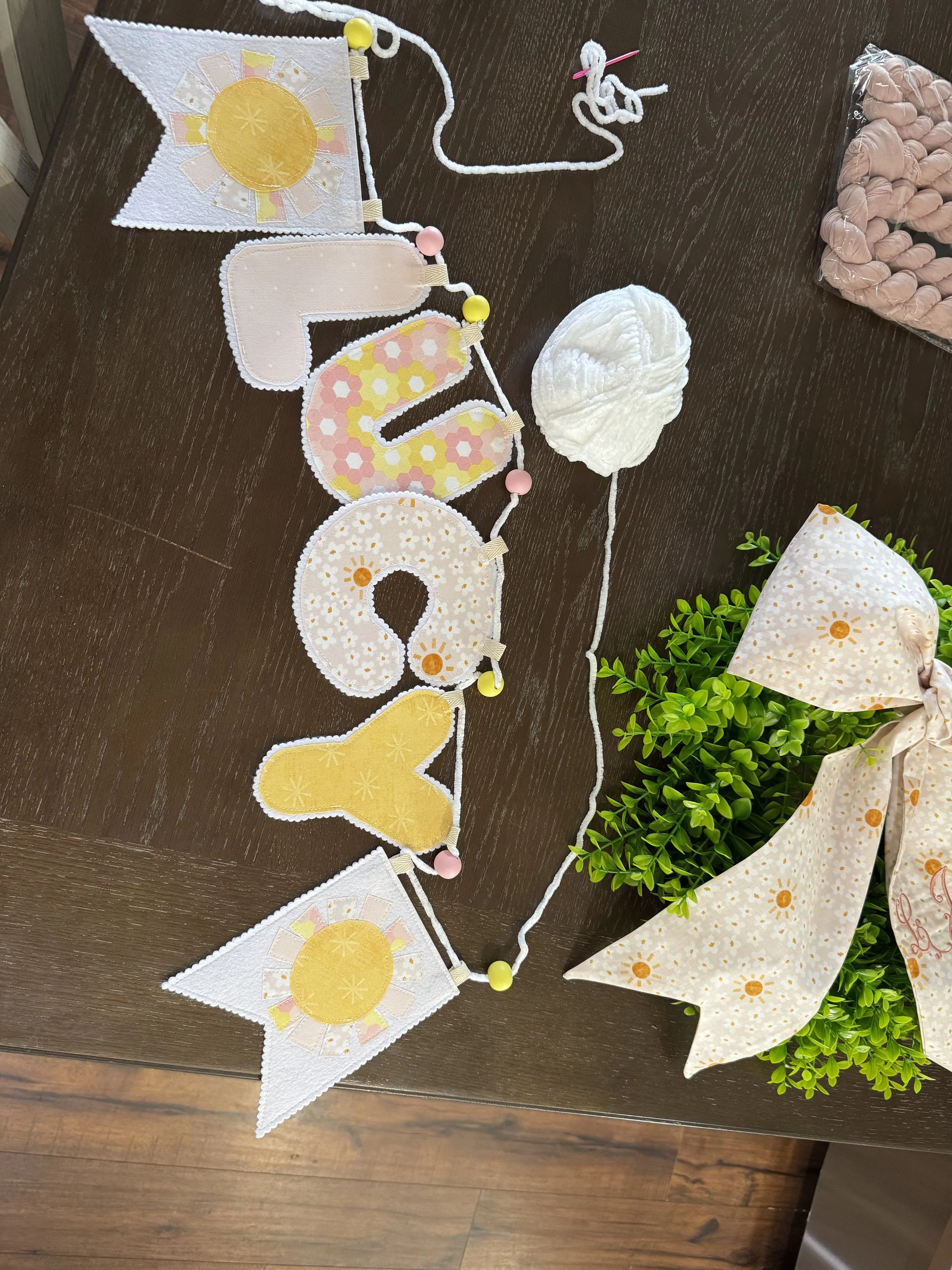 Handmade fabric pennant garland in coordinating pink and yellow prints with decorative beads for nursery decor.