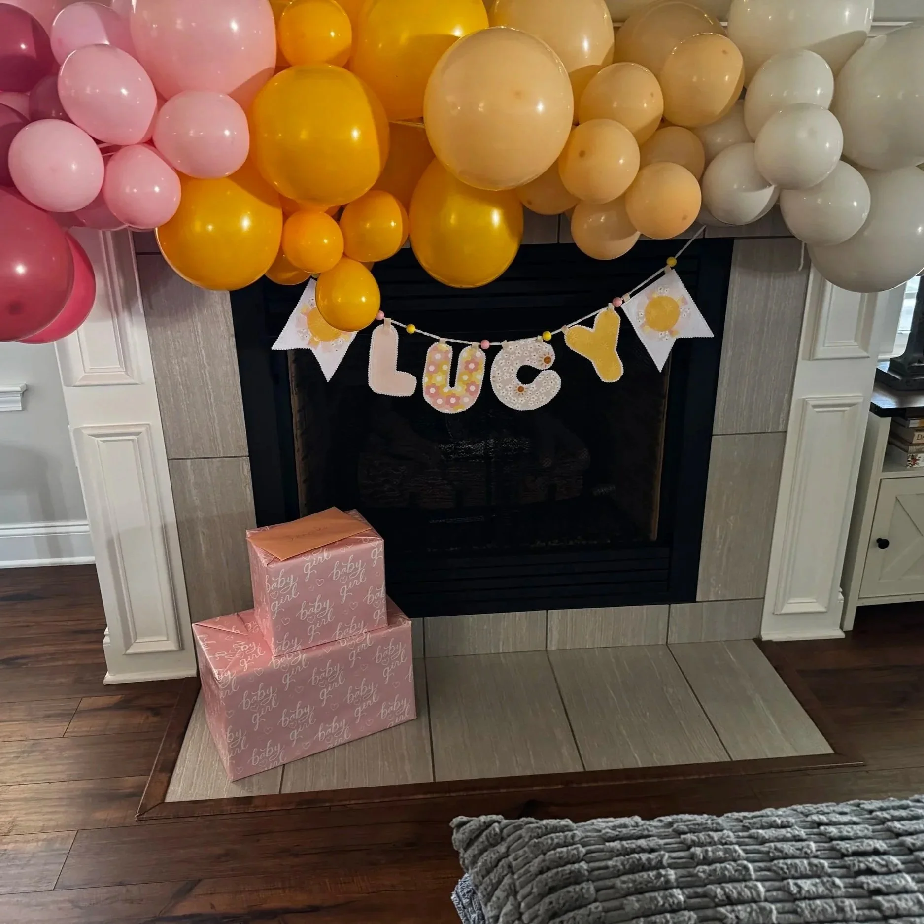 Personalized LUCY fabric name banner displayed with coordinating sunshine accents, pink and yellow balloons and handmade nursery decorations.
