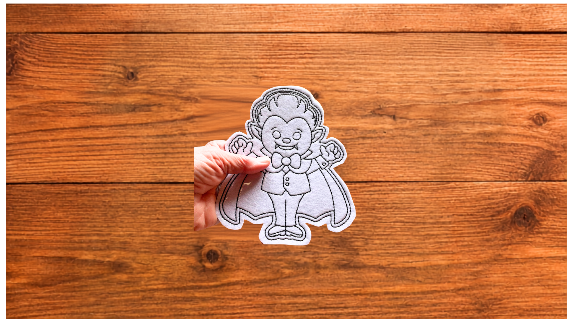 Hand holding reusable vampire Coloring Cutie showing size and stitched details