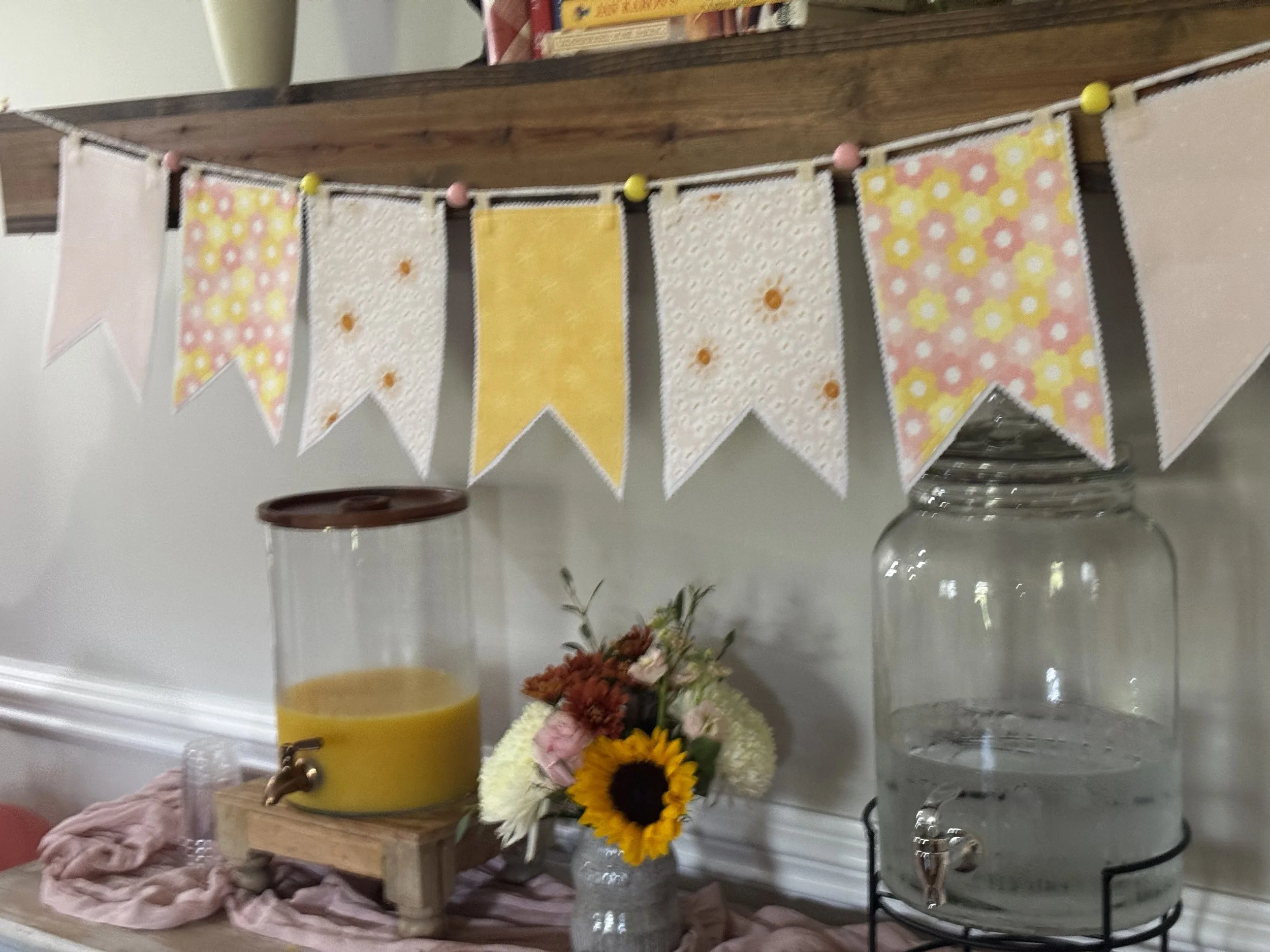 IMG_0372.jpegClose-up of handmade fabric pennants featuring yellow, pink and floral cotton fabrics with decorative stitching and finished edges.