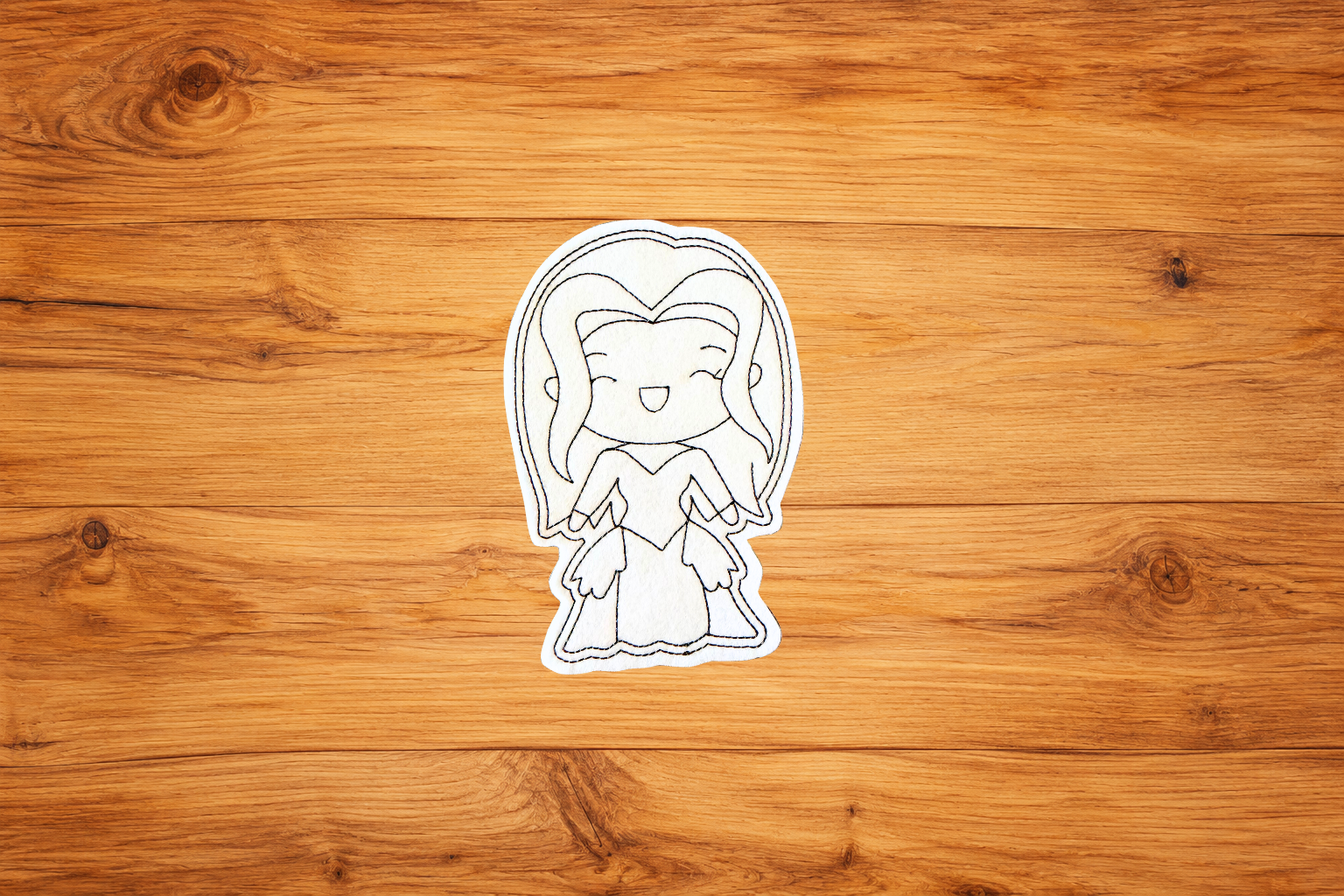 Handmade Witchy Woman Coloring Cutie with long hair and embroidered outlines on a warm wood background