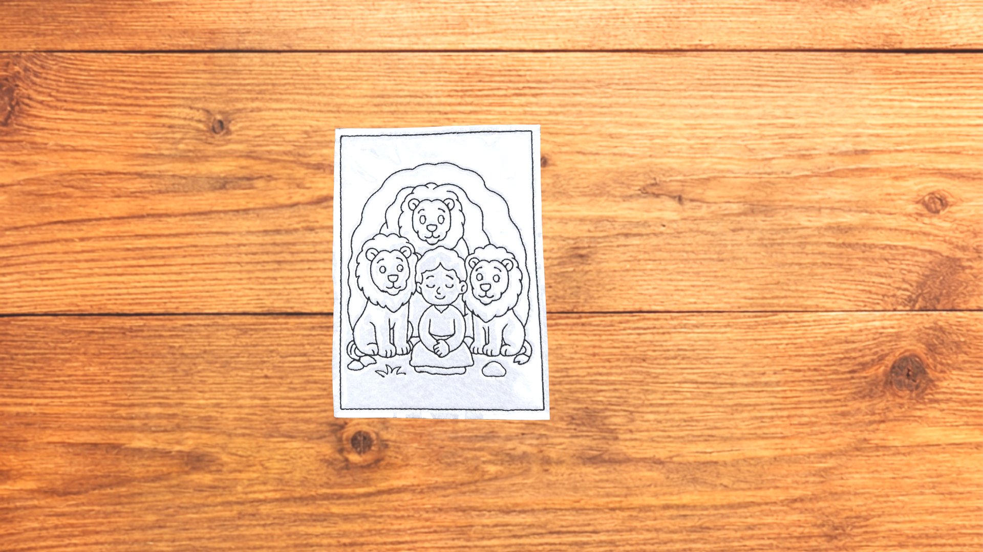 Daniel in the lion's den reusable Bible Story Coloring Cutie activity card on wooden background