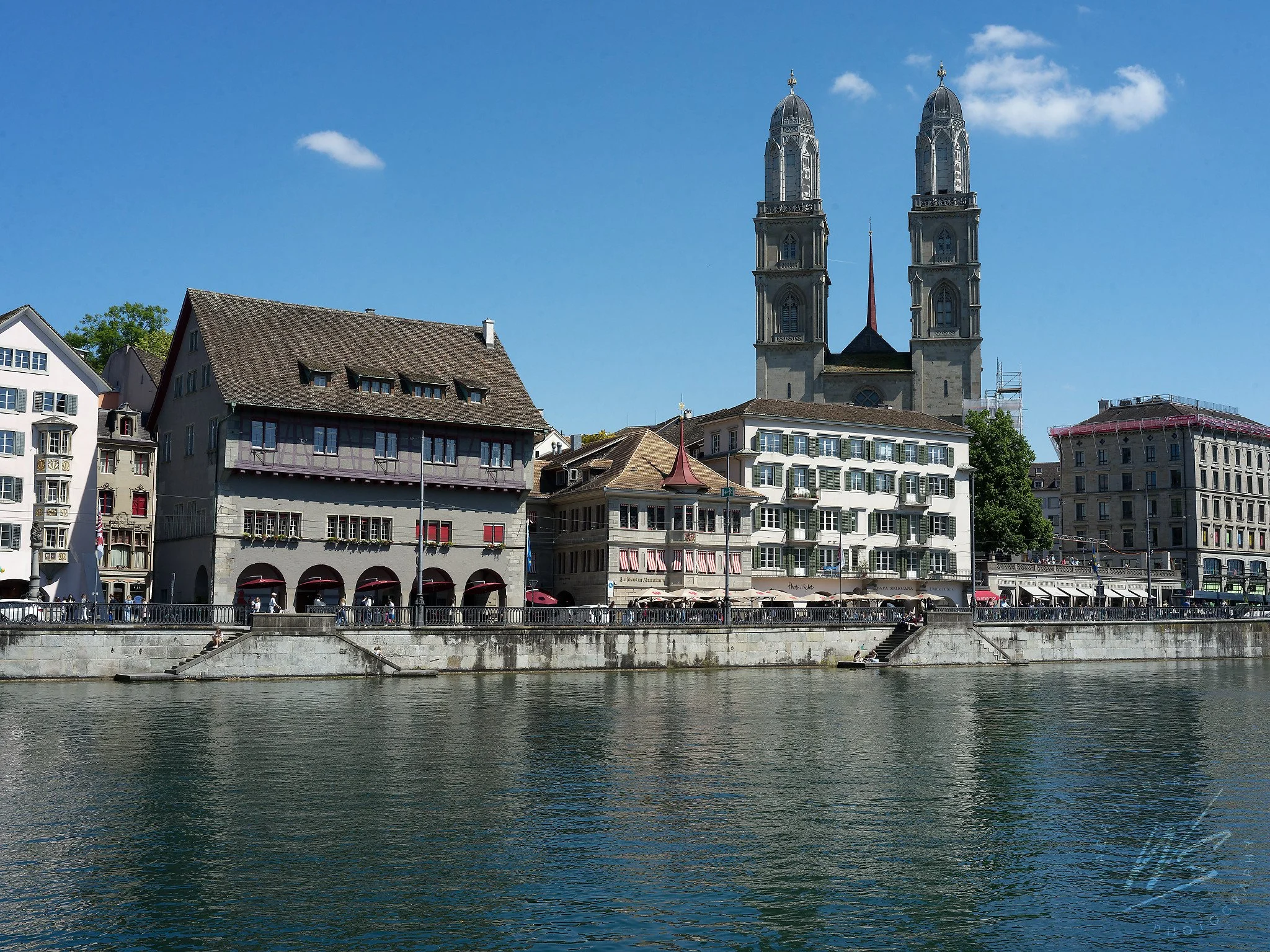 The Limmatquai waterfront and the twin Romanesque towers of the Grossmünster cathedral, Zurich, Switzerland. The Grossmünster — founded according to legend by Charlemagne — was the church of Huldrych Zwingli, where the Swiss Protestant Reformation be