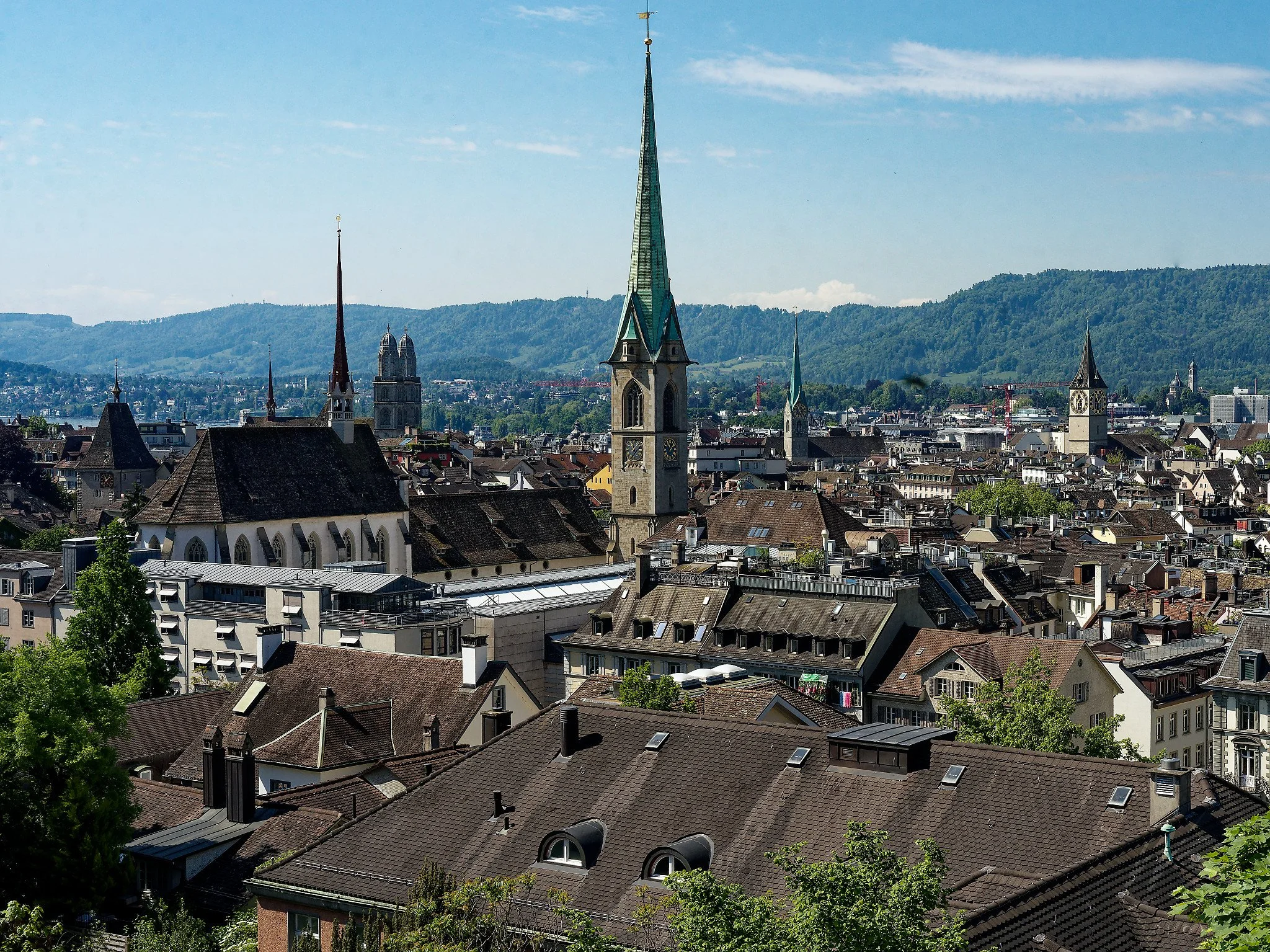 Panoramic view over the rooftops of Zurich Old Town from the Lindenhügel hill, Zurich, Switzerland. From left to right: the Augustinerkirche, the twin towers of the Grossmünster, the Predigerkirche, the soaring green spire of the Fraumünster, and the