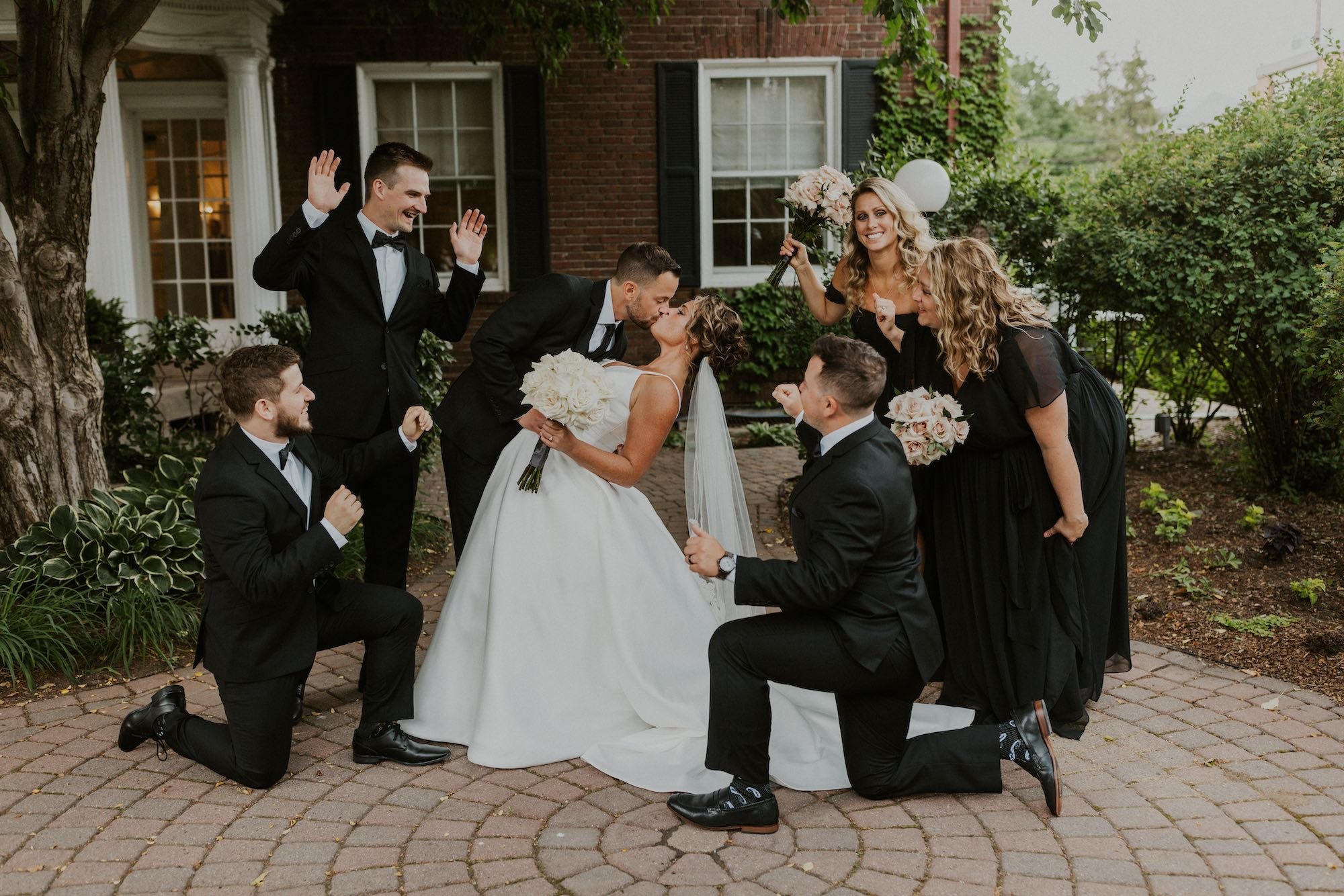bride and groom kissing surrounded by wedding party.jpg