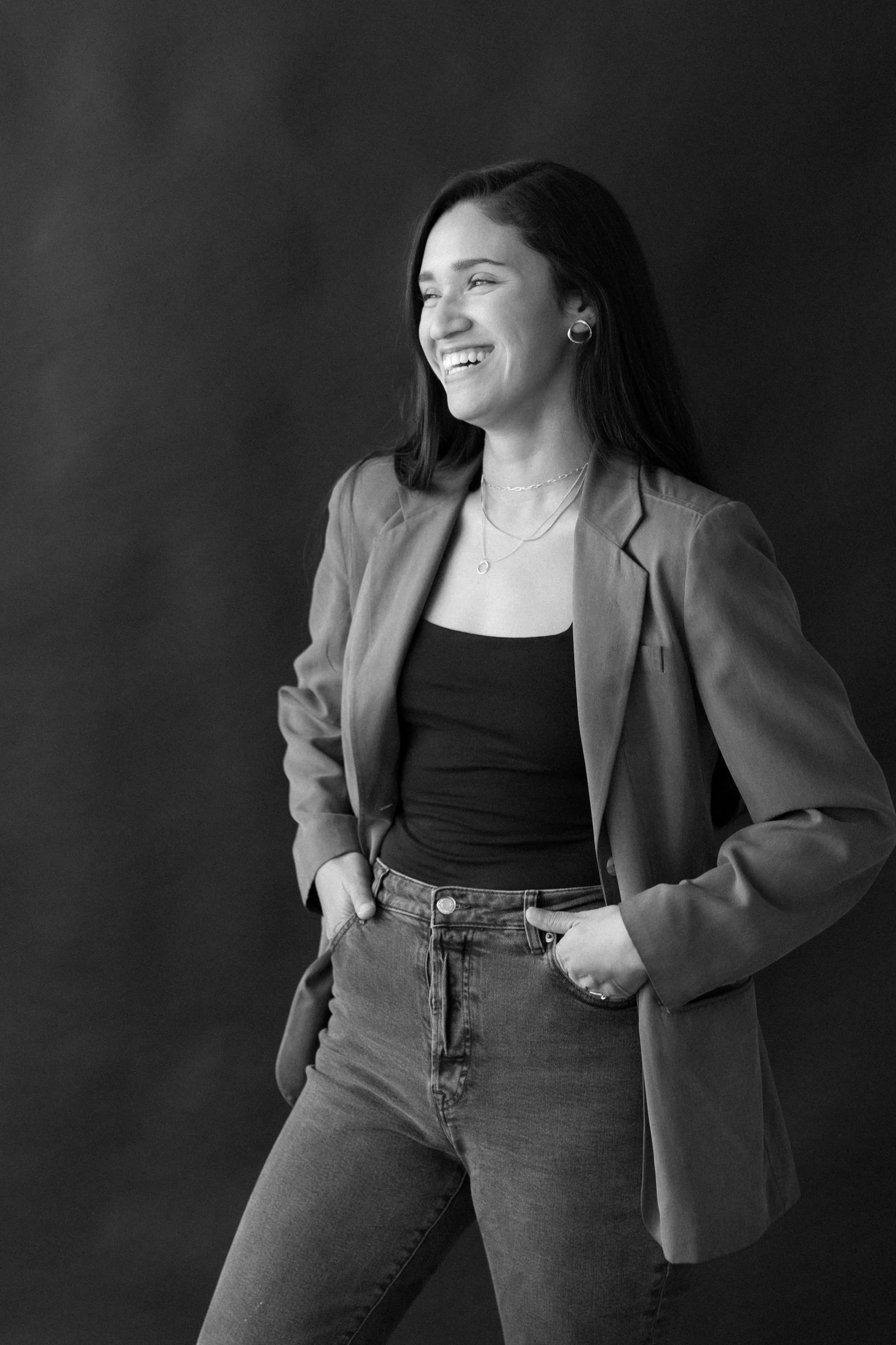 Black and white headshot of Dina Diaz, a California wedding and brand photographer, smiling and looking off to side
