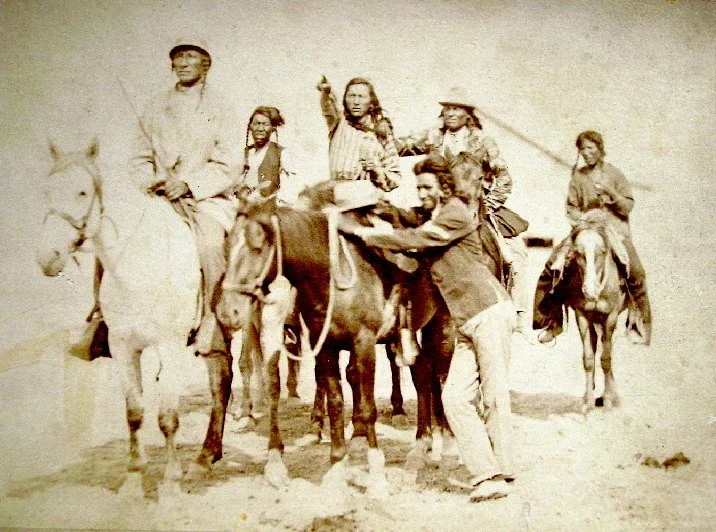 Apsáalooke (Crow) men on horseback, several holding feathered staffs, photographed by David F. Barry between 1878 and 1883.