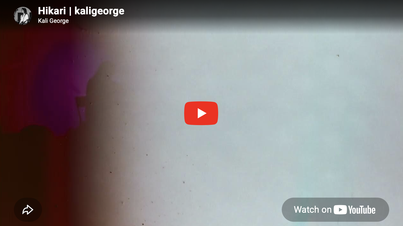 Blurred background with some purple and pink hues, indicating a video thumbnail on a YouTube page with the title 'Hikari | kaligeorge' and the name Kali George.
