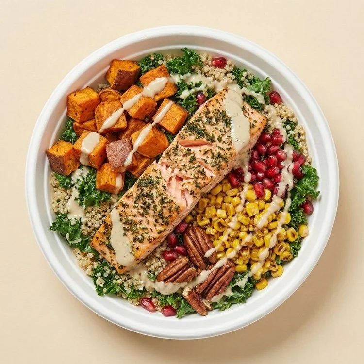 Bowl saludable con cubos de salmón horneado, camote dulce, quinoa y nueces sobre base de vegetales verdes.