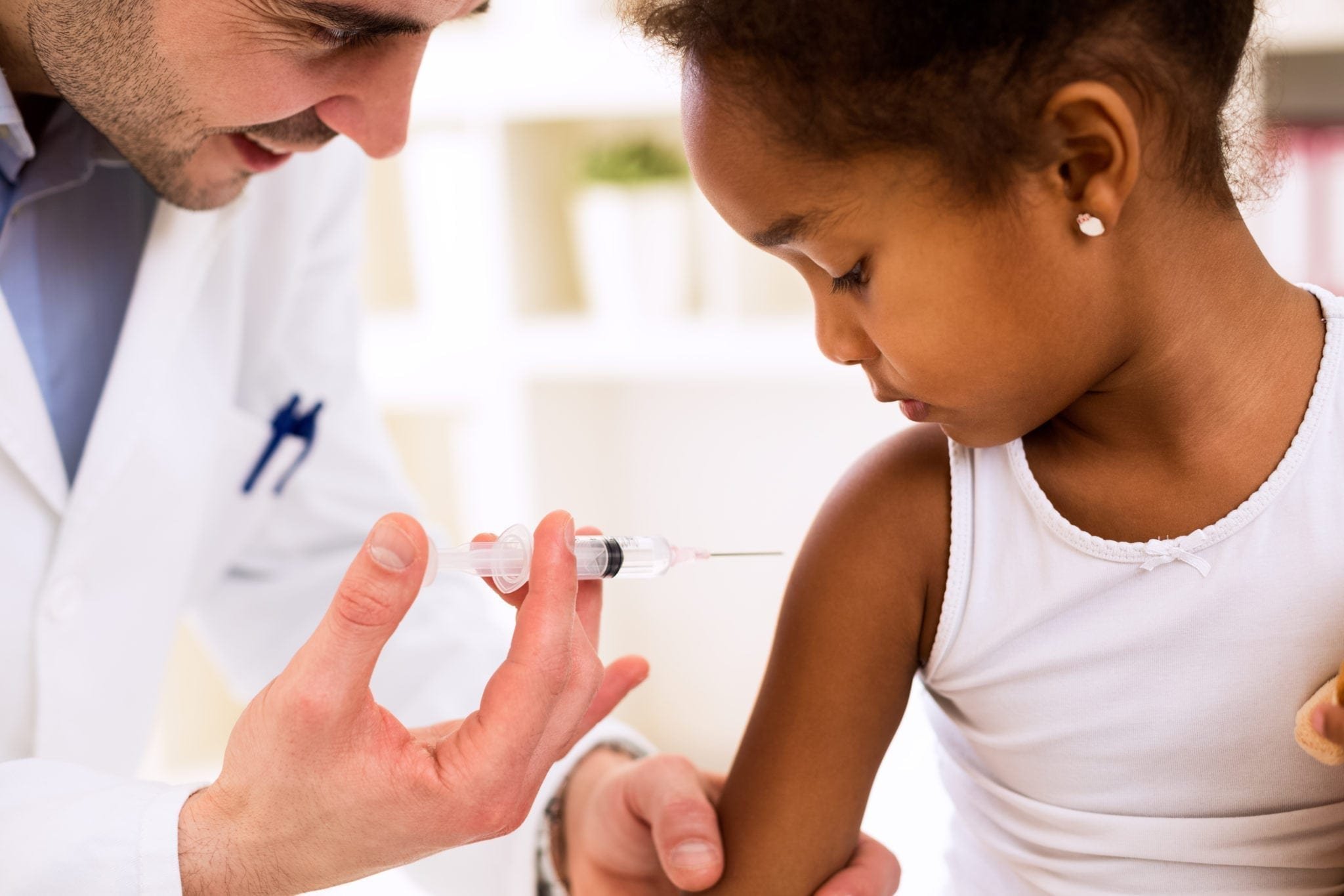 A healthcare professional administering a vaccine to a young girl in a clinical setting.