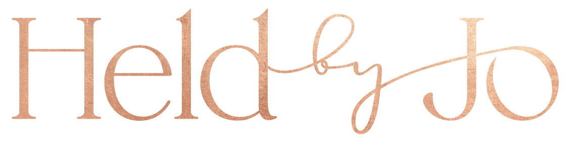 The phrase 'Held by Jo' written in a metallic, elegant script font.