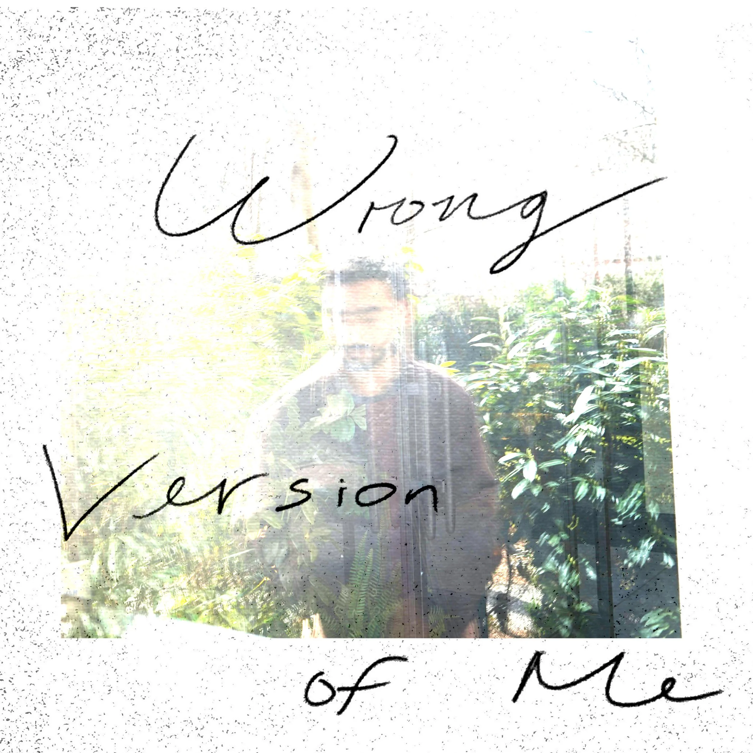 A person standing outdoors near green plants, with text overlay that reads 'Wrong Version of Me' in cursive handwriting. This is the cover art for Michael Isaak's 2025 single "Wrong Version of Me"