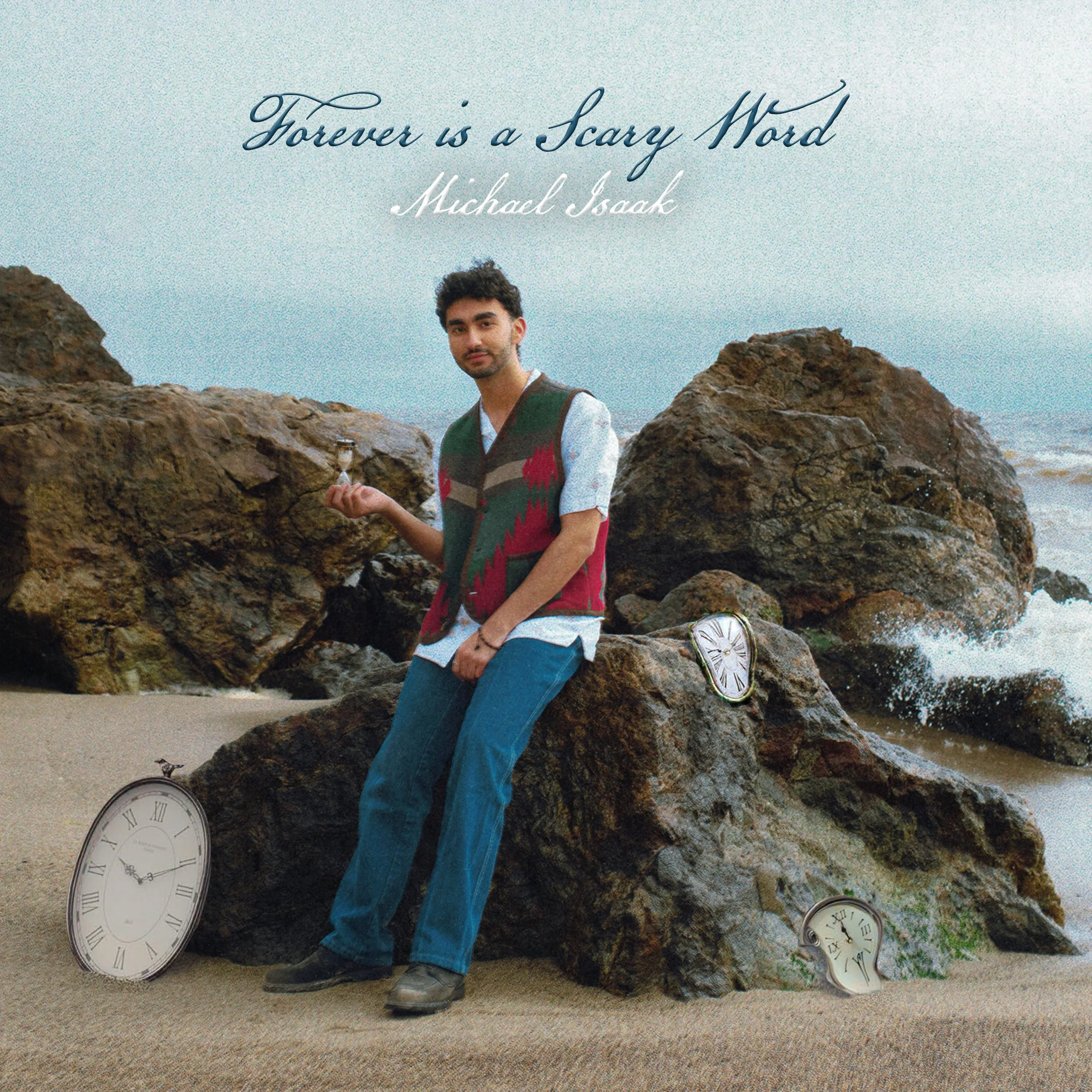 A person sitting on a large rock on a beach, holding an hourglass, with broken clocks on the rocks around them, with an ocean in the background. This is the album cover for Michael Isaak's 2024 EP Forever is a Scary Word