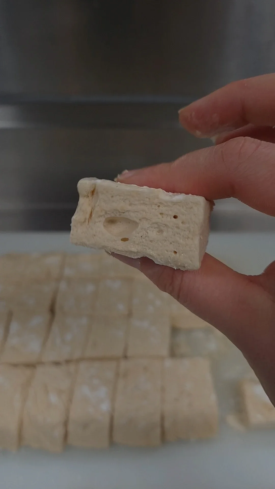 Soft sugar-free marshmallow being gently squished between fingers, showing its fluffy texture and perfect homemade consistency.