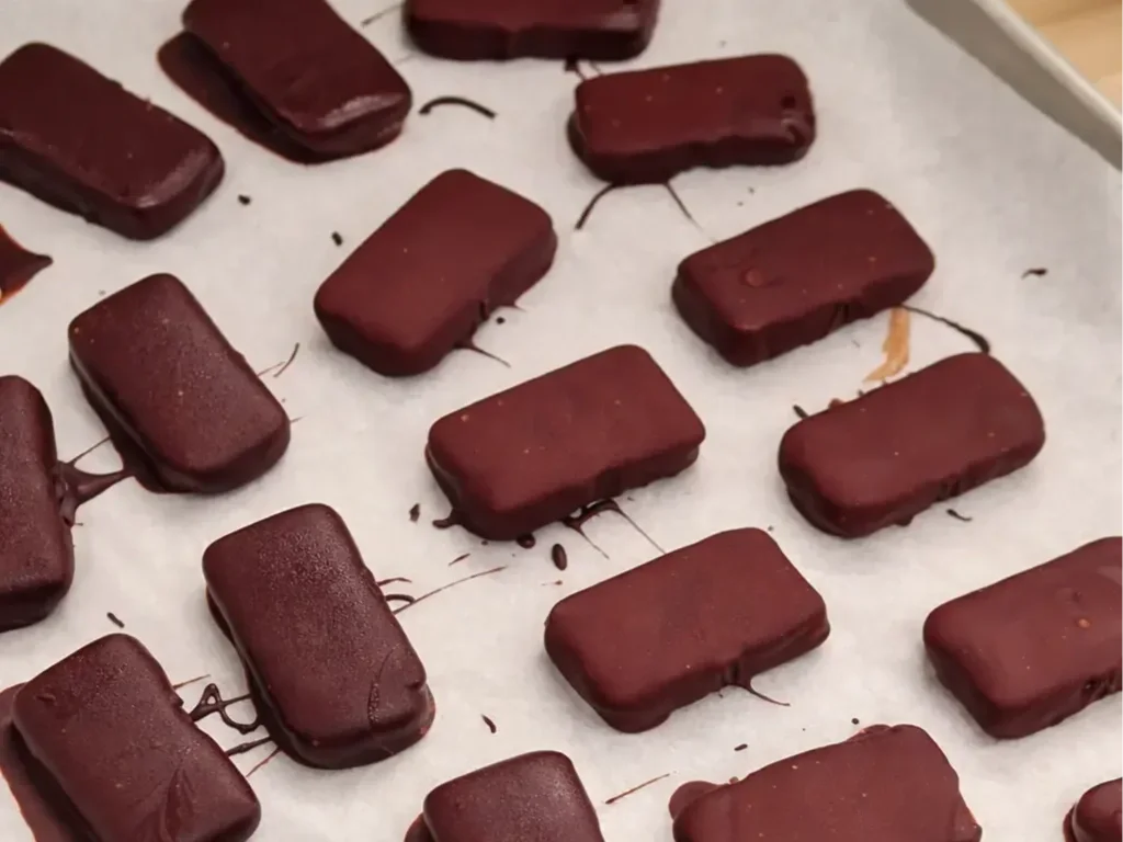 Tray of freshly coated peanut butter date chocolate cups setting, gluten-free and easy Valentine’s Day treat.