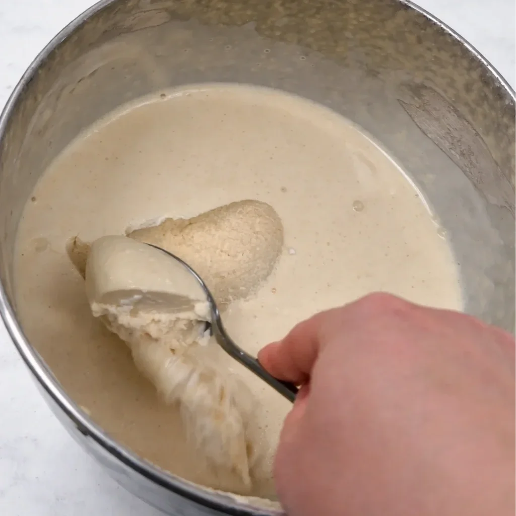 Firm dairy-free pina colada mousse set in a bowl with spoon showing light airy texture, refined sugar free dessert.