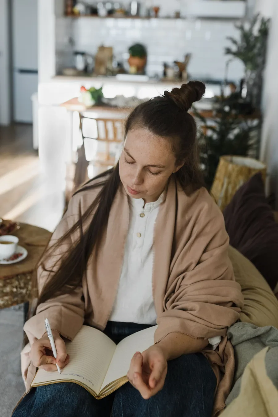 Woman journaling with tea at home, representing personalised gut and hormone health support.
